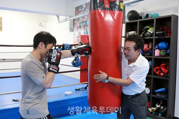 김광선 관장이 샌드백을 몸소 잡아 준 채로 제자에게 펀치를 날리는 법을 가르치고 있다. ©홍남현